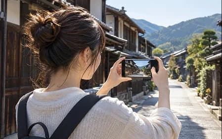 古い町並みでスマートフォンを構えて撮影する女性